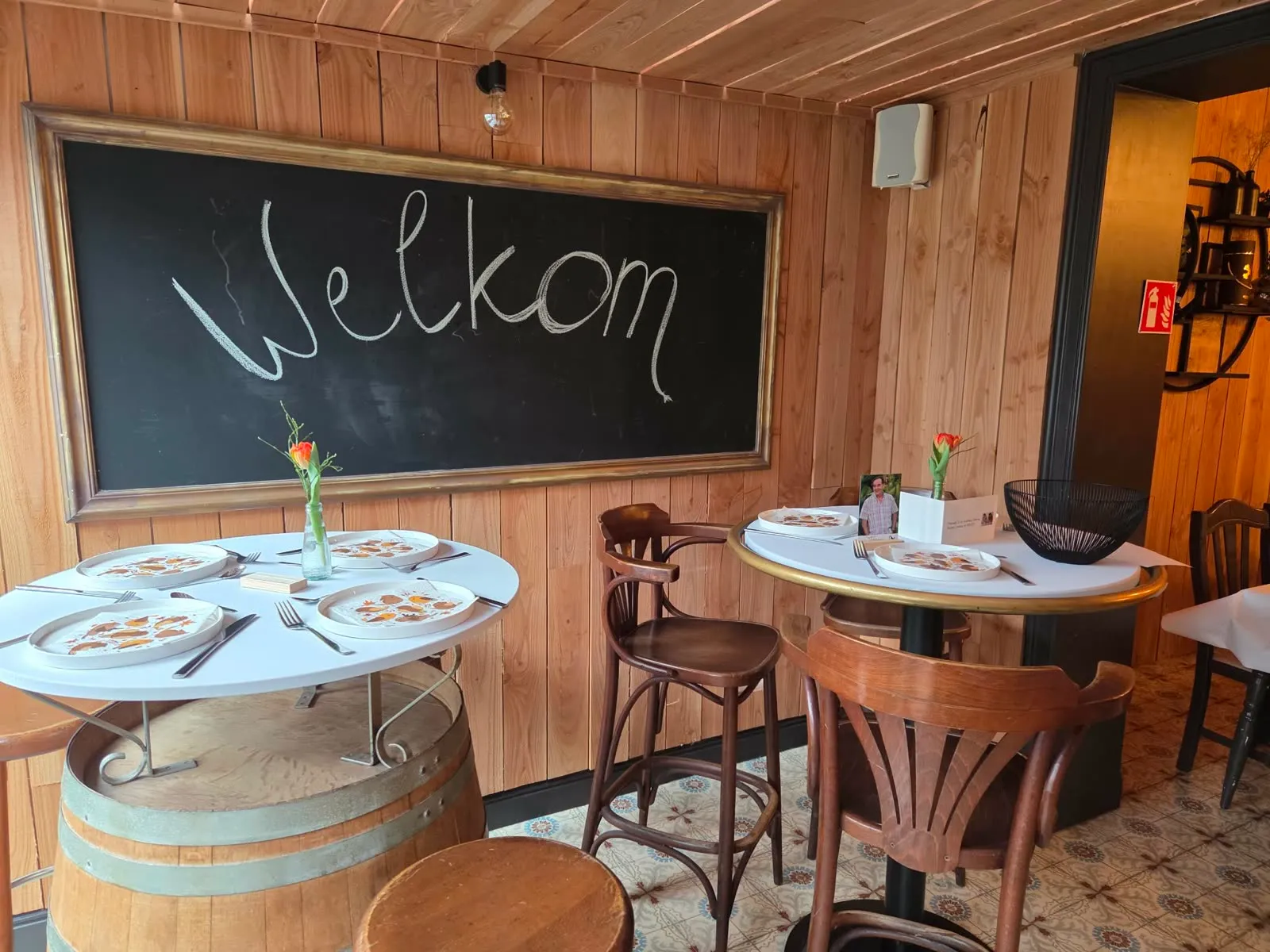 Krijtbord met 'Welkom' boven tafels op wijnvaten