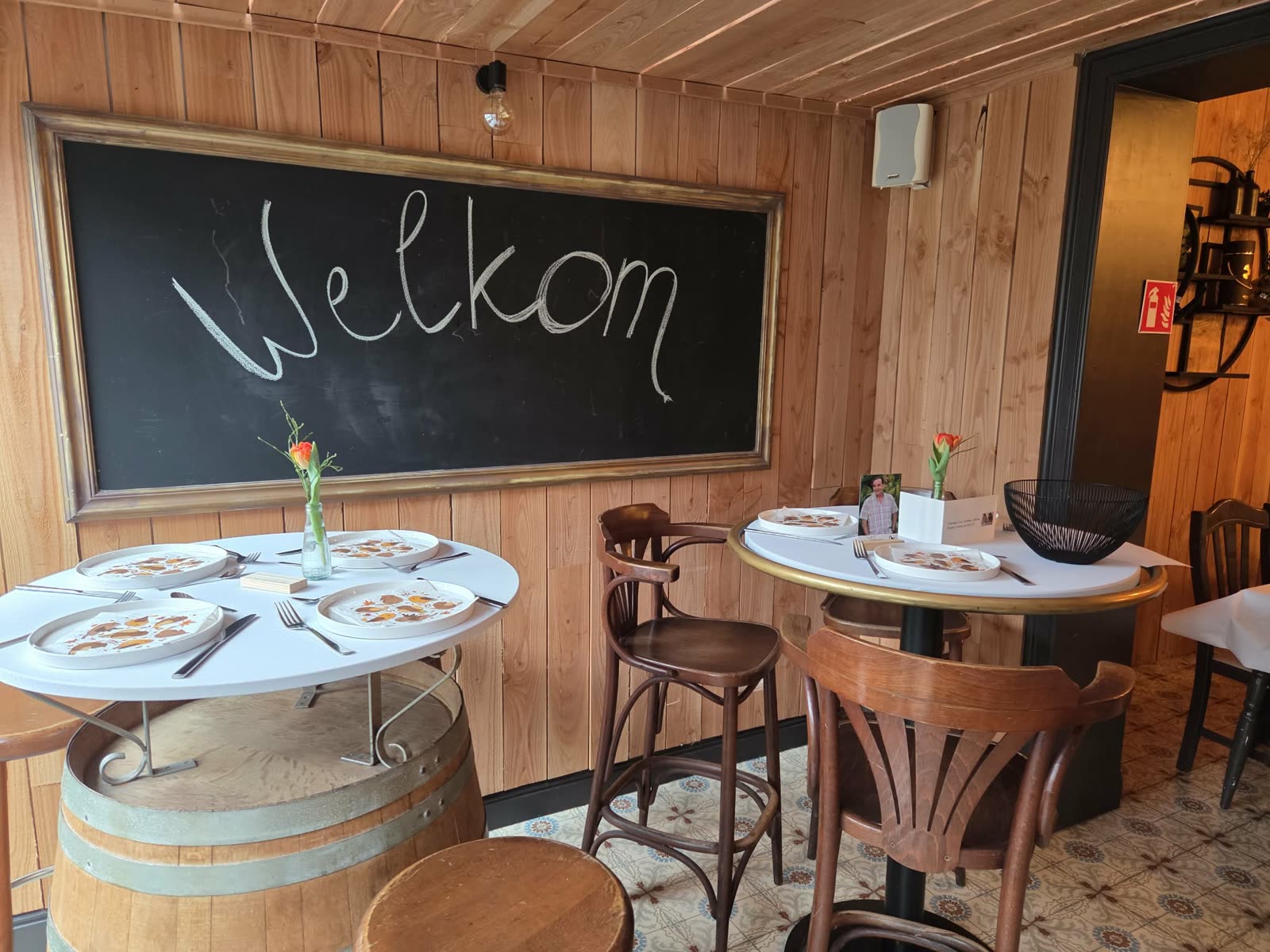 Krijtbord met 'Welkom' boven tafels op wijnvaten